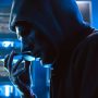 A hacker wearing a mask to cover his face is using computer to hack data to get ransom from victims. A hacker wearing a mask to cover his face is using computer to hack data to get ransom from victims.