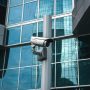 External surveillance camera against glass building facade External surveillance camera against glass building facade
