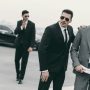 happy businessman walking with bodyguards and talking by smartphone happy businessman walking with bodyguards and talking by smartphone